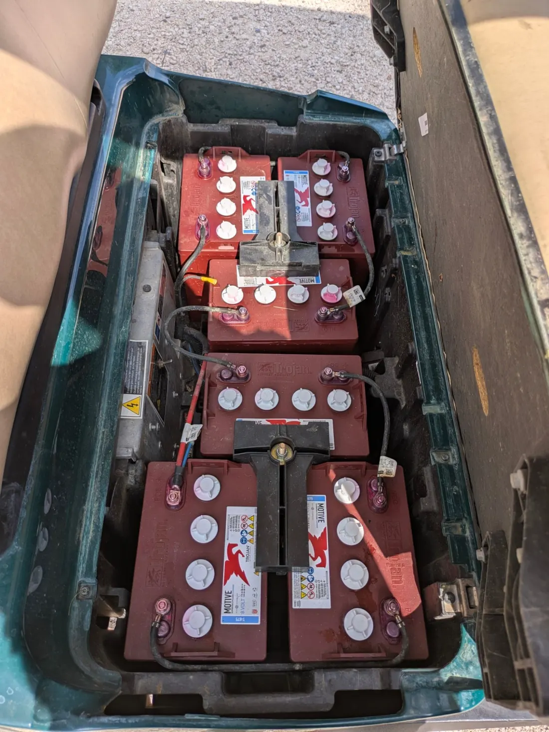 Vano batterie di un golf cart Club Car con sei batterie al piombo da 8 V collegate in serie, con i tappi delle celle sulla sommità.